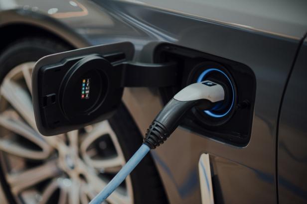 Nahaufnahme eines Elektroautos, das an einer Ladestation angeschlossen ist.