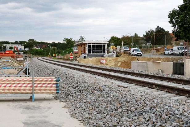 Gleisbau mit Schienen, Schotter und Baustellenfahrzeugen an einer Kurve.