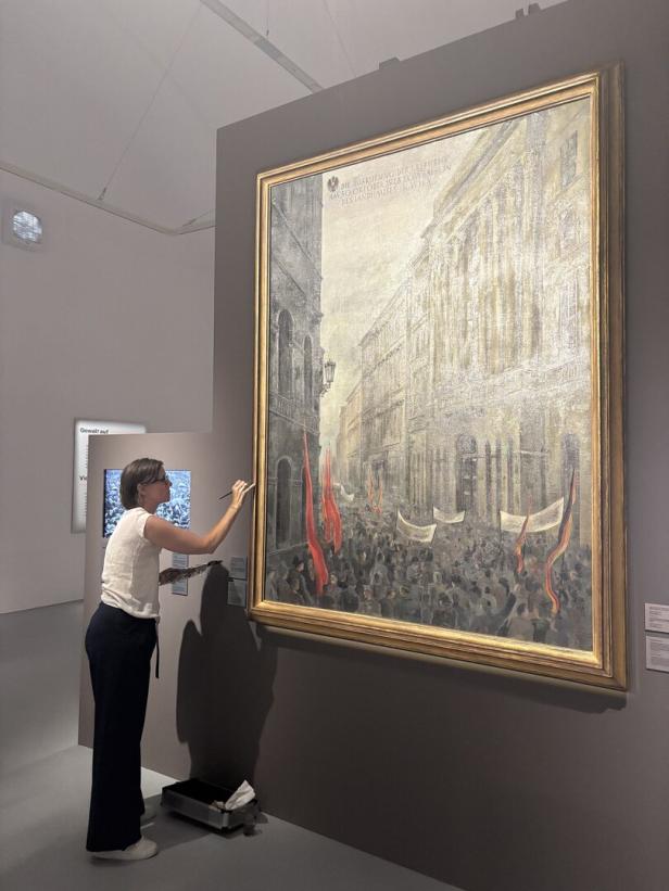 Eine Frau restauriert ein großes historisches Gemälde im Museum.
