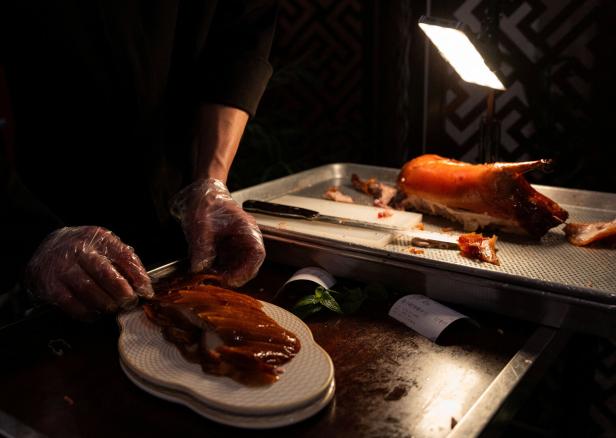 A chef serves a roasted Peking duck at a table at Mantang Peking Duck restaurant in Beijing