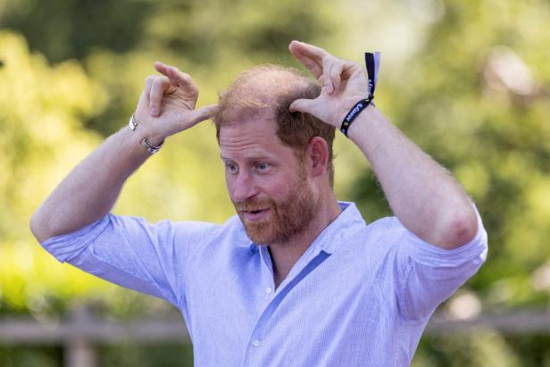 Prinz Harry macht mit seinen Händen Hasenohren über seinem Kopf.