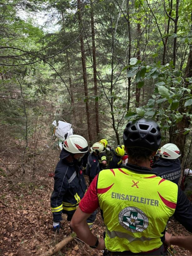 Einsatzkräfte der Feuerwehr und des Bergrettungsdienstes Österreich bei einem Unfall in einem Waldgebiet.