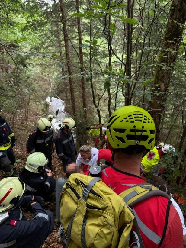 Einsatzkräfte der Feuerwehr und des Bergrettungsdienstes Österreich bei einem Unfall in einem Waldgebiet.