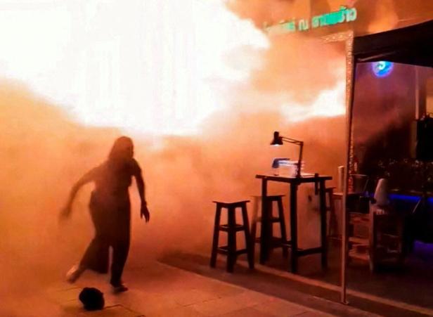 A person runs as flames rise at a pub in Bangkok