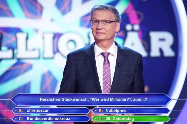 Moderator vor Quiz-Hintergrund mit Multiple-Choice-Frage zu „Wer wird Millionär?“.