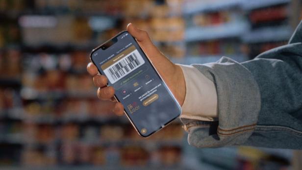 Hand hält ein Smartphone mit digitaler Karte und Barcode vor unscharfen Regalen.
