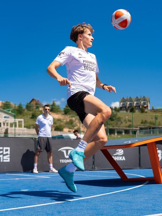 Junger Mann springt auf einem Teqballfeld einem Ball entgegen.