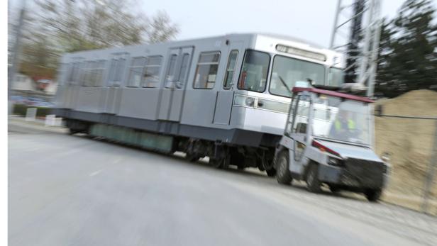 Eine U-Bahn fährt an einem kleinen Transportfahrzeug vorbei.