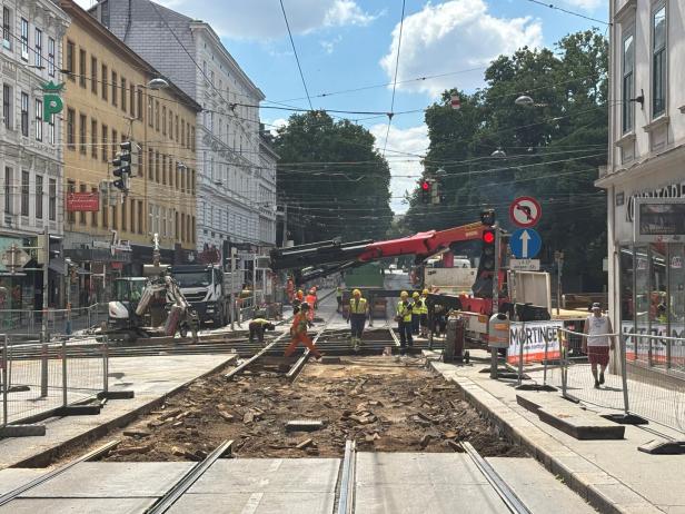 Straßenbahngleise werden von Arbeitern und Baufahrzeugen auf einer gesperrten Stadtstraße erneuert.