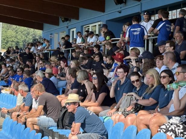 Volle Tribüne bei einer Sportveranstaltung mit vielen Zuschauern in blauen Sitzreihen.