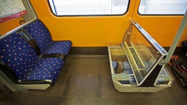 Innenansicht eines U-Bahn-Waggons mit blauen Sitzen und gelben Wänden.
