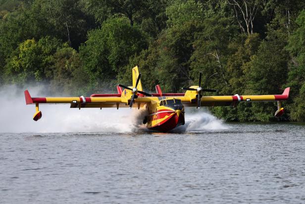 Firefighting Canadair aircraft skims the surface of the Seine River while collecting water in Ivry-sur-Seine
