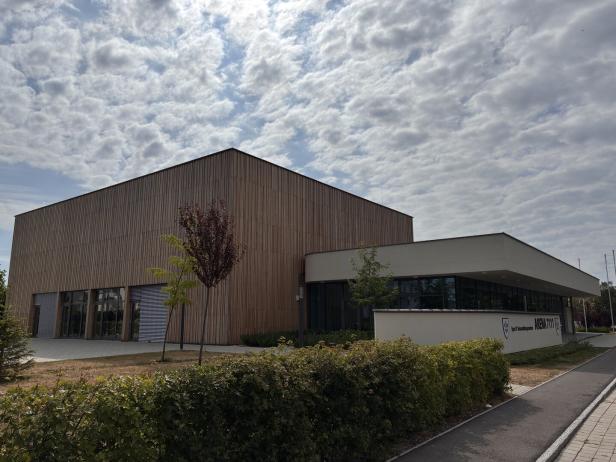 Das Sport- und Veranstaltungszentrum Arena 7111 mit Holzfassade unter einem bewölkten Himmel.