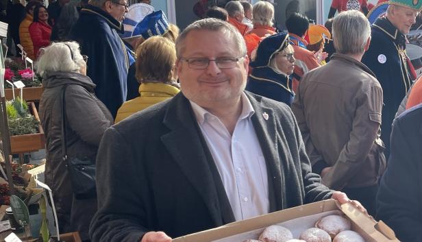 Andreas Kutheil auf einem Fest mit Krapfen in der Hand.