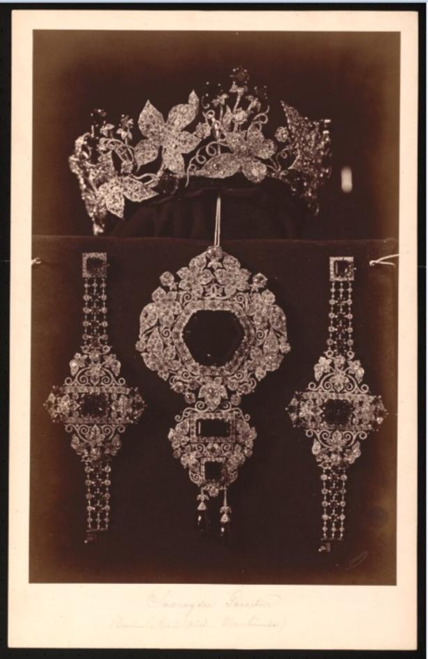 Historisches Schmuckensemble mit Diadem, Halscollier und zwei langen Ohrringen auf dunklem Hintergrund.