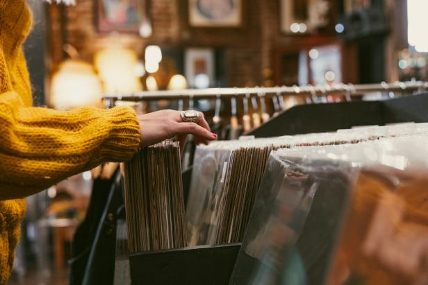 Person searching through vinyl albums in a nostalgic secondhand shop