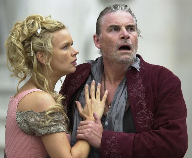 SALZBURGER FESTSPIELE/"JEDERMANN" Eine blonde Frau hält einen erschrockenen Mann fest, der mit offenem Mund in eine Richtung starrt.