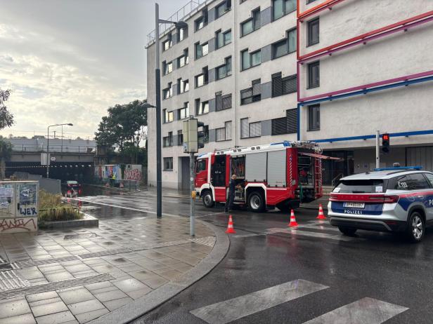 Feuerwehr und Polizei sperren die überflutete Unterführung, in der ein Auto im Wasser steckt. 
