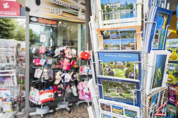 Postkartenständer vor einem Souvenirshop mit Ansichten vom Wörthersee und Schloss Velden.
