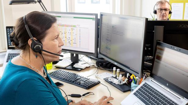Mitarbeiterin arbeitet mit Headset an mehreren Monitoren im Büro.