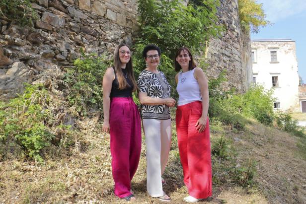Drei Frauen stehen vor einer alten Steinmauer am Kunstmuseum Waldviertel und präsentieren die neue Kultur-Partnerschaft.
