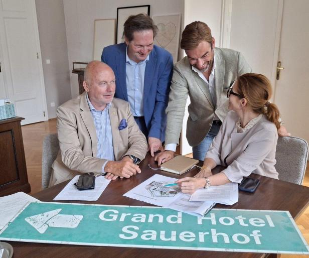 Vier Personen sitzen an einem Tisch und besprechen Pläne.