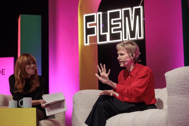 Zwei Frauen sprechen auf einer pink beleuchteten Bühne unter dem Schriftzug „FLEM“.