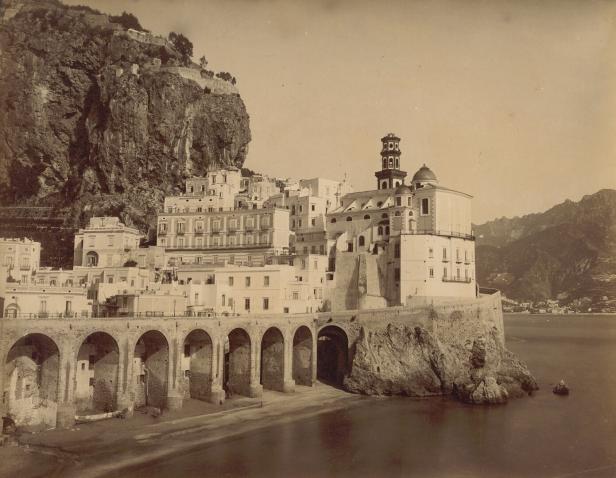Historische Küstenstadt mit weißen Gebäuden an steiler Felsklippe über dem Meer.