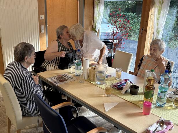 Vier ältere Frauen sitzen an einem Tisch in einem hellen Raum und unterhalten sich.