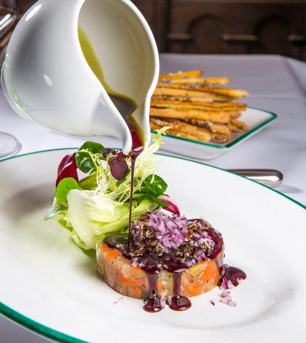 Feines Gourmetgericht mit Gemüse-Tatar, Salat und Sauce, angerichtet auf einem Teller.
