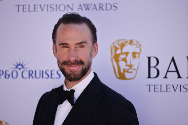 Joseph Fiennes trägt einen schwarzen Smoking mit Fliege vor einer BAFTA Television Awards-Kulisse.