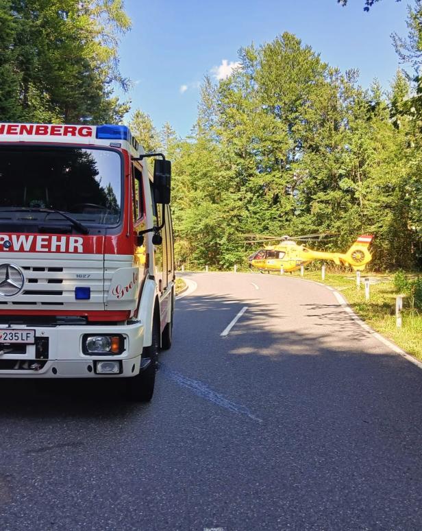 Feuerwehrwagen und Rettungshubschrauber auf gesperrter Waldstraße.