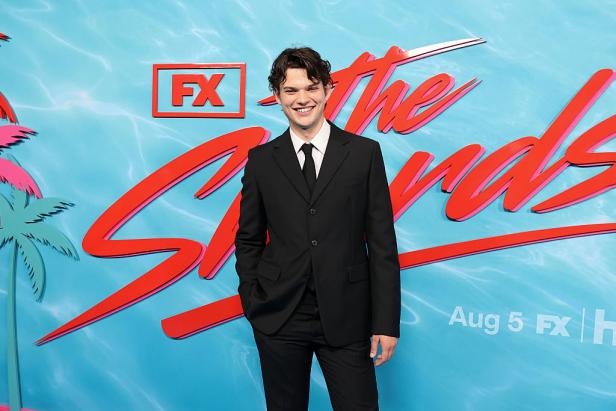 Homer Gere lächelt im schwarzen Anzug vor der FX-Premierenwand von „The Shards“ in New York.