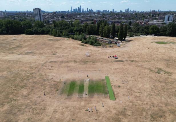 Drone view of cricket match on parched grassland, Hackney Marshes in London