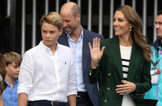 Prinz William, Prinzessin Kate und Prinz George bei einem öffentlichen Auftritt, bei dem Kate freundlich in die Menge winkt.