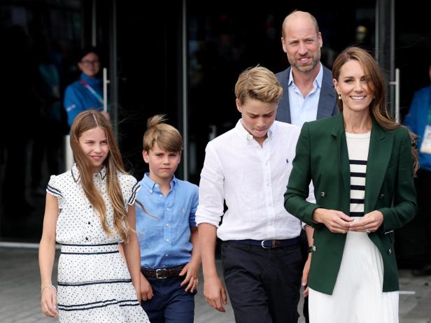 Prinz William und Prinzessin Catherine gehen mit ihren Kindern George, Charlotte und Louis vor einem Gebäude.