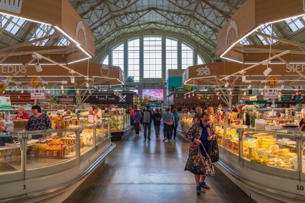 Bunte Markthalle in Riga mit vielen Ständen und Menschen unter hohem Glasdach.