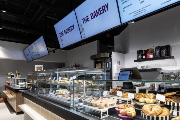 Bäckerei-Café mit belegten Backwaren und Kuchen im Verkaufsbereich.