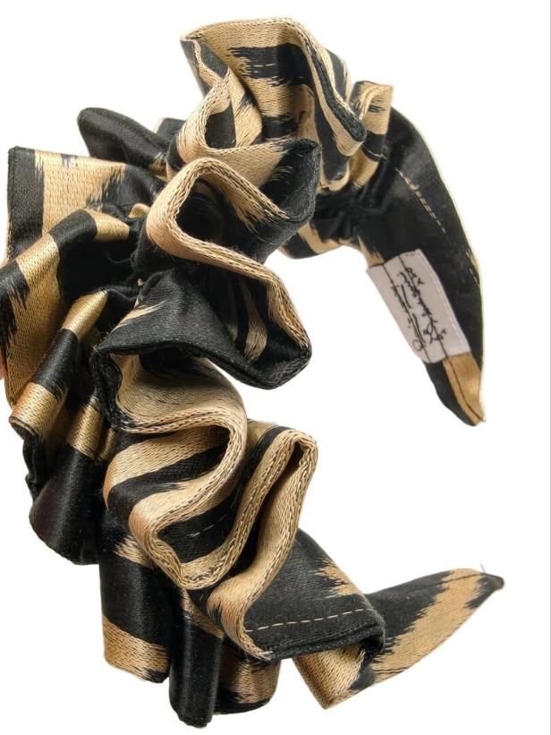 Schwarzer und goldener Haargummi mit gerüschter Schleife auf weißem Hintergrund.