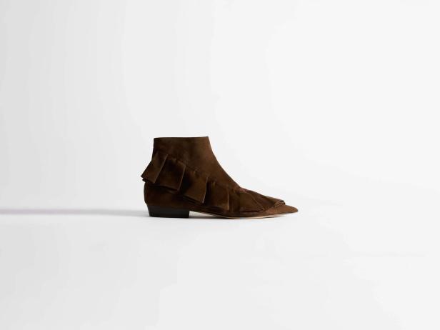 Brauner Stiefelettenschuh mit Rüschen auf weißem Hintergrund.