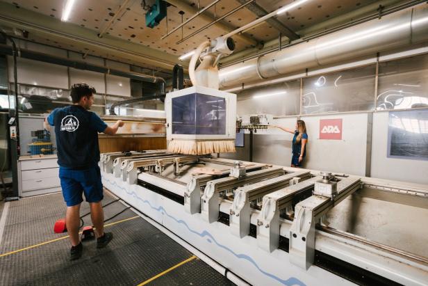 Zwei Personen bedienen eine große CNC-Fräse in einer Werkhalle.