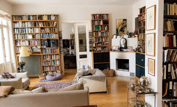 Ein gemütliches Wohnzimmer mit hohen Bücherregalen, einem Kamin, bequemen Sofas und einem Parkettboden.