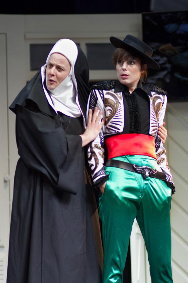 Eine Nonne berührt die Schulter einer Person im Stierkämpferkostüm.