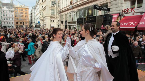 Zwei Frauen in weißen Kleidern geben sich vor einer Menschenmenge die Hand.