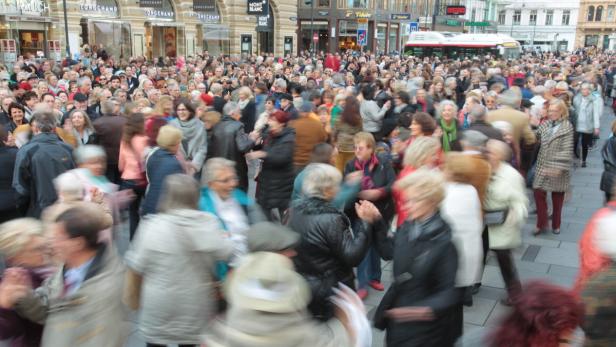 Eine große Menschenmenge bewegt sich auf einer belebten Straße in der Stadt.