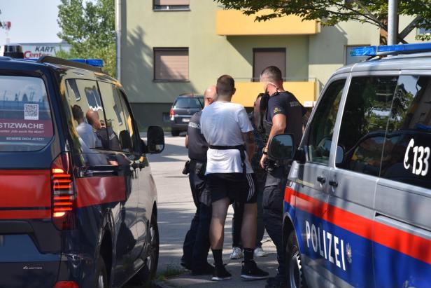 Polizisten nehmen einen Mann zwischen Einsatzfahrzeugen fest.