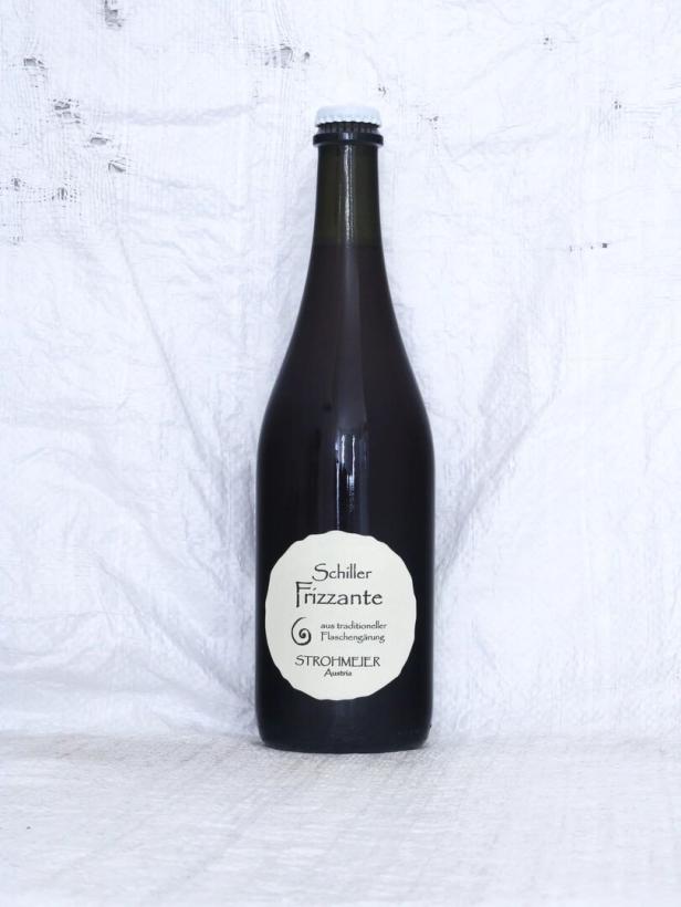 Eine Flasche Schiller Frizzante von Strohmeier aus Österreich vor einem weißen, strukturierten Hintergrund.
