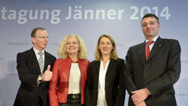 Vier Personen posieren vor einem Hintergrund mit der Aufschrift „Tagung Jänner 2014“.
