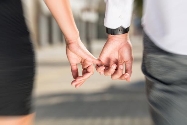 close up photo of young couple holding hands on street in summer