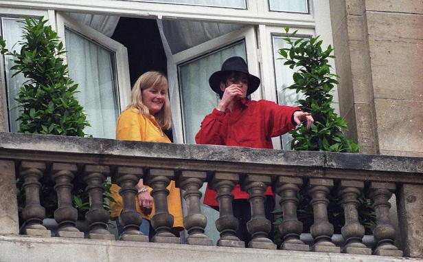 Debbie Rowe und Michael Jackson 1997 in Paris auf einem Balkon stehend. Jackson zeigt nach unten, Rowe lächelt.